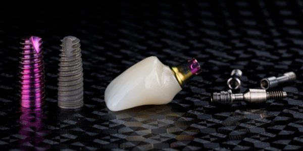 Two different dentals implant and crown of ceramics on black textured background